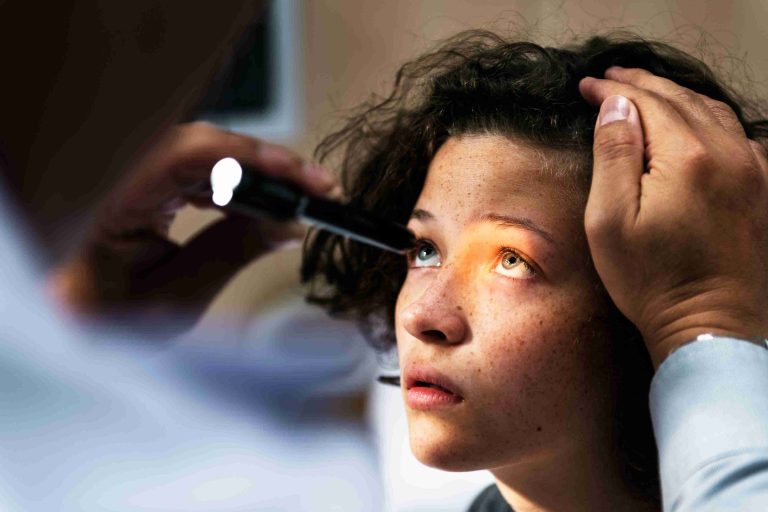 Teen getting her eye checked by an eye doctor.